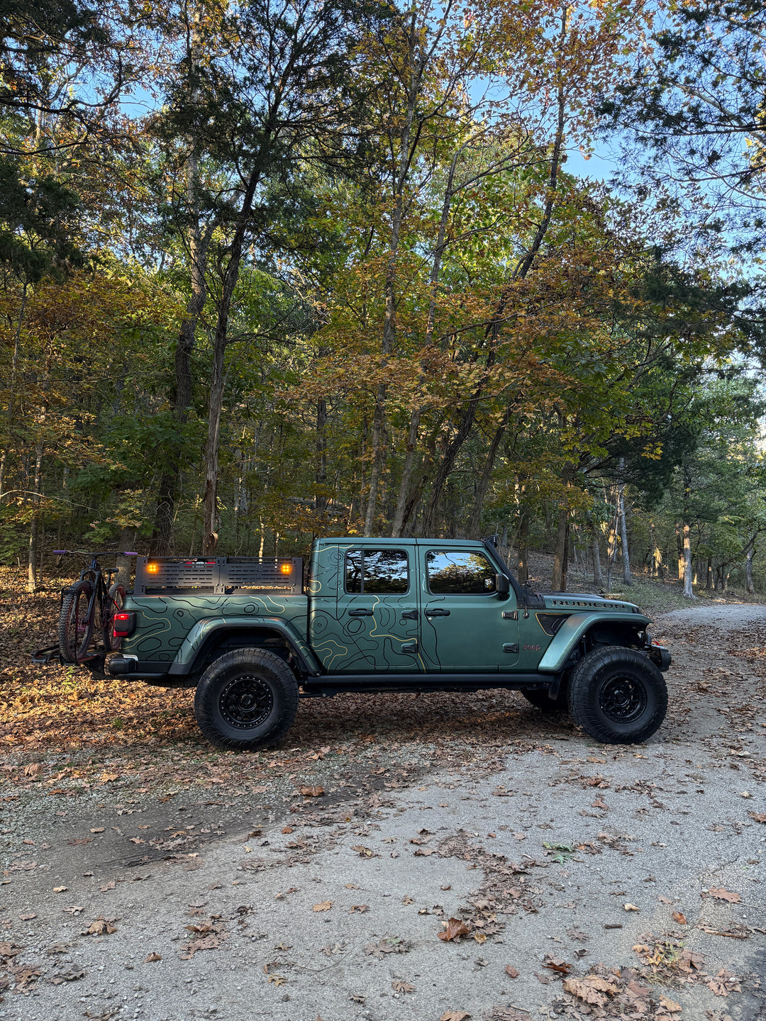 Side profile of a green truck with DIY Topo Kit topographic lines in a fall forest
