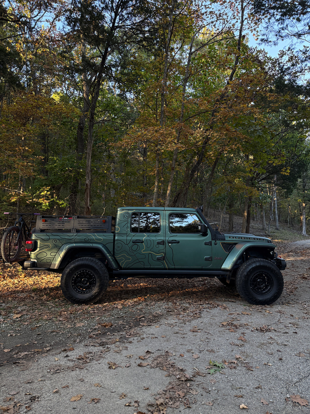 Wide side view of a truck with topo kit graphics in a fall forest