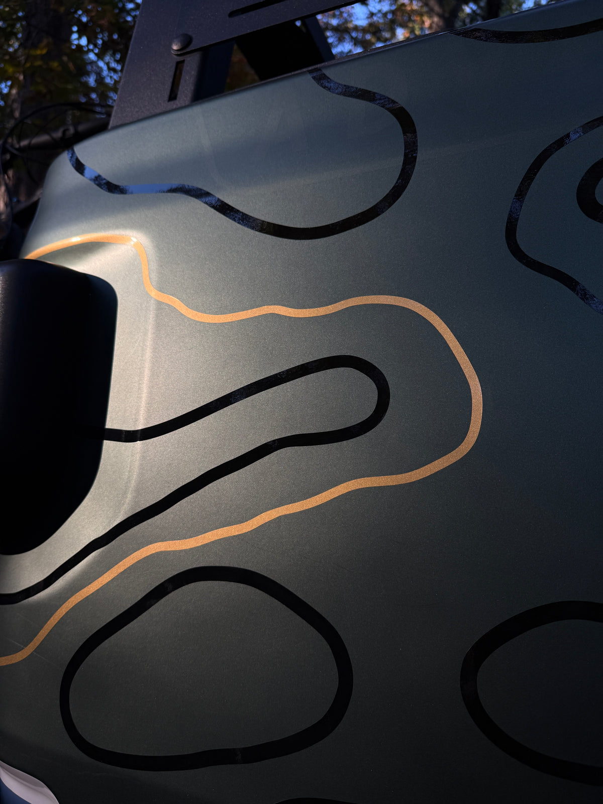 Close-up of a metallic gold topo accent line between black topo lines
